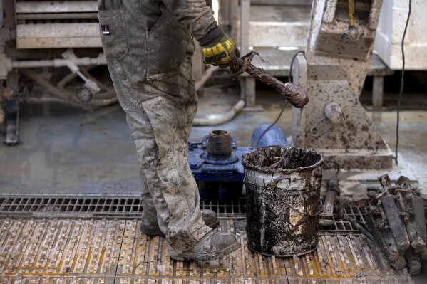A rig operator applies mud to lubricate drills that will reach reservoirs of heat underground, in a process developed by Fervo Energy, on Sunday, Nov. 26, 2023, near Milford, Utah. In Nevada, Fervo Energy's first operational project has begun pumping carbon-free electricity onto that state's electric grid to power Google data centers, Google announced Tuesday, Nov. 28. That pilot will help Fervo launch projects like this one in Utah to deliver far more carbon-free electricity to the grid. (AP Photo/Ellen Schmidt)