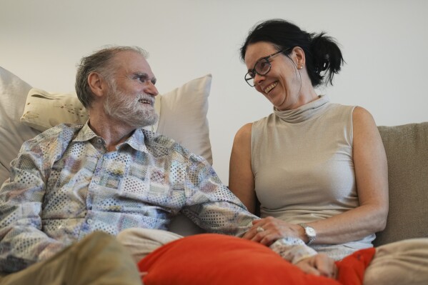 Michael Bommer, left, who is terminally ill with colon cancer, looks at his wife Anett Bommer during a meeting with The Associated Press at his home in Berlin, Germany, Wednesday, May 22, 2024. Bommer, who has only a few more weeks to live, teamed up with friend who runs the AI-powered legacy platform Eternos to "create a comprehensive, interactive AI version of himself, allowing relatives to engage with his life experiences and insights," after he has passed away. (AP Photo/Markus Schreiber)