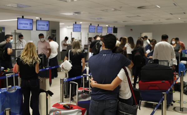 FILE - In this April 17, 2021, file photo, people check in for a flight to Miami at Silvio Pettirossi Airport, in Luque, Paraguay. Vaccine seekers who can afford to travel are coming to the United States to avoid the long wait, including people who have come from as far as Paraguay.  (AP Photo/Jorge Saenz, File)