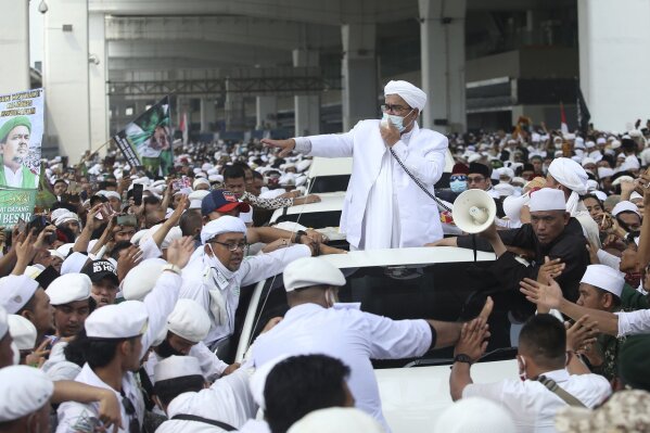 Indonesian Islamic cleric and the leader of Islamic Defenders Front Rizieq Shihab, center, speaks to his followers upon arrival from Saudi Arabia at Soekarno-Hatta International Airport in Tangerang, Indonesia, Tuesday, Nov. 10, 2020. Thousands of followers of the firebrand cleric joyfully welcomed him at an the airport as he returned home from a 3-year exile in Saudi Arabia after criminal charges including a pornography case were dropped. (AP Photo)