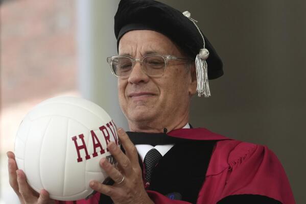 Actor Tom Hanks examines a ball as part of a spoof during Harvard University commencement exercises on the school's campus, Thursday, May 25, 2023, in Cambridge, Mass. Hanks was awarded an honorary degree of Doctor of Arts during the ceremonies. (AP Photo/Steven Senne)