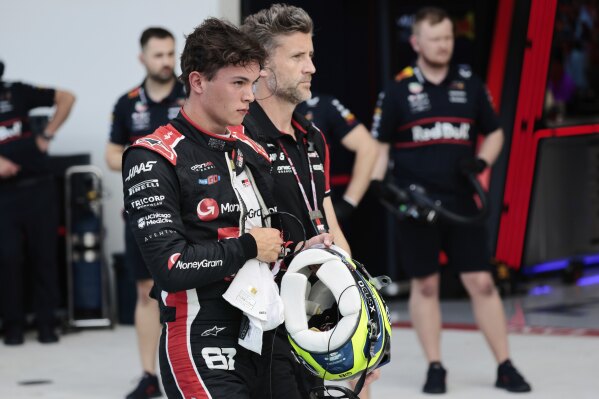 Haas driver Oliver Bearman of Britain, left, walks through the pit area after being eliminated during the qualifying session for the Formula One Miami Grand Prix auto race at the International Autodrome, Saturday, May 3, 2025, in Miami Gardens, Fla. (Shawn Thew/Pool Photo via AP)
