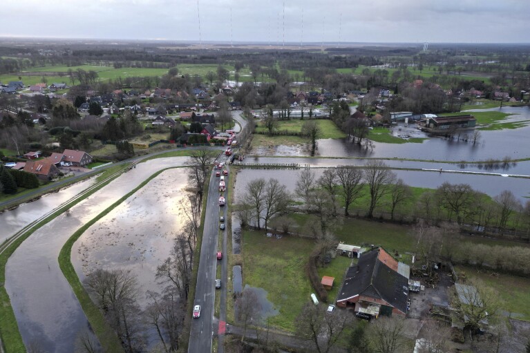 In het midden zijn brandweerlieden te zien terwijl ze het gebied met zandzakken beschermen tegen overstromingen nadat de Burlage-Langholder Dyff, een zijrivier van de Leda, op dinsdag 26 december 2023 in Langholt, Duitsland, overstroomde.  Brandweerlieden en vrijwilligers gingen aan de slag.  In Noord- en Oost-Duitsland duwden zware regenval rivieren en beken over hun oevers en dwongen ze de evacuatie van inwoners in veel steden om de dammen te versterken tegen het stijgende water in Noord- en Oost-Duitsland.  (Lars Benning/dpa via AP)