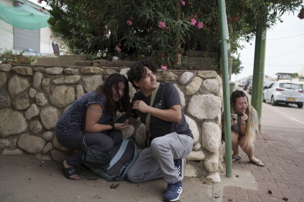 Israelis take cover from the incoming rocket fire from the Gaza Strip in Ashkelon, southern Israel, Wednesday, Oct. 11, 2023. (AP Photo/Leo Correa)