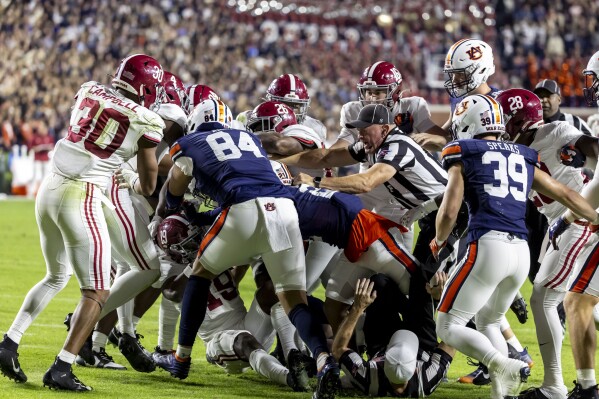 FILE - Referees try to break up an altercation between Alabama and Auburn during the second half of an NCAA college football game, Saturday, Nov. 25, 2023, in Auburn, Ala. A settlement being discussed in an antitrust lawsuit against the NCAA and major college conferences could cost billions and pave the way for a new compensation model for college athletes. (AP Photo/Vasha Hunt, File)