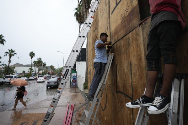 Employees cover the windows of a souvenirs store with wood in preparation for the arrival of the hurricane Norma, in Cabo San Lucas, Mexico, Friday, Oct. 20, 2023. Hurricane Norma is heading for the resorts of Los Cabos at the southern tip of Mexico's Baja California Peninsula, while Tammy grew into a hurricane in the Atlantic. (AP Photo/Fernando Llano)