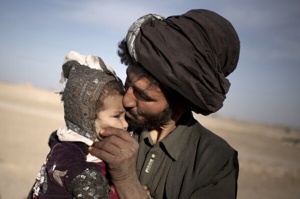 FILE - A nomad kisses his young daughter while watching his herd in Marjah, Helmand province, Afghanistan, Oct. 20, 2012. (AP Photo/Anja Niedringhaus, File)