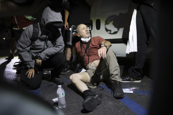 Protesters help news photographer Nick Stern after an injury during a protest in Compton, Calif., Saturday, June 7, 2025, after federal immigration authorities conducted operations. (AP Photo/Ethan Swope)