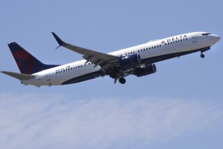 FILE- In this May 24, 2018, file photo a Delta Air Lines passenger jet plane, a Boeing 737-900 model, approaches Logan Airport in Boston.  Airlines are seeing a sharp drop in bookings and a rise in cancellations in recent days as the coronavirus outbreak continues to spread, and they are responding by slashing flights and freezing hiring.   Normally airlines try to lure reluctant customers by discounting fares, but that won't work in the face of the COVID-19 outbreak. (AP Photo/Charles Krupa, File)