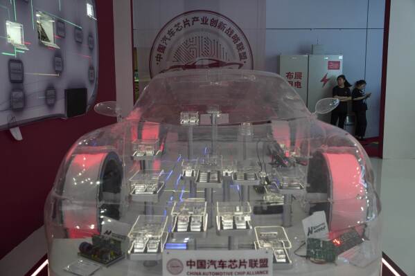 Workers stand near a model demonstrating products from the China Automotive Chip Alliance during the Shanghai auto show on Thursday, April 24, 2025. (AP Photo/Ng Han Guan)