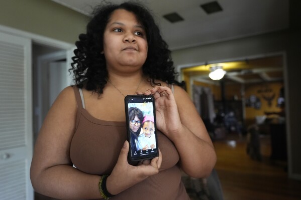 Sima Gutierrez shows a photo of herself with her mother, during an interview, Monday, March 25, 2024, in Flint, Mich. It was a decade ago that she complained her stomach hurt when she drank water. (AP Photo/Carlos Osorio)