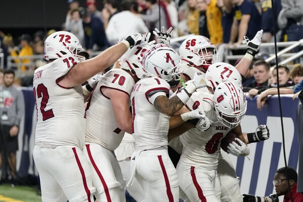 Miami (Ohio) running back Rashad Amos (0) is swarmed by teammates after a 10-yard rushing touchdown during the second half of the Mid-American Conference championship NCAA college football game, Saturday, Dec. 2, 2023, in Detroit. (AP Photo/Carlos Osorio)