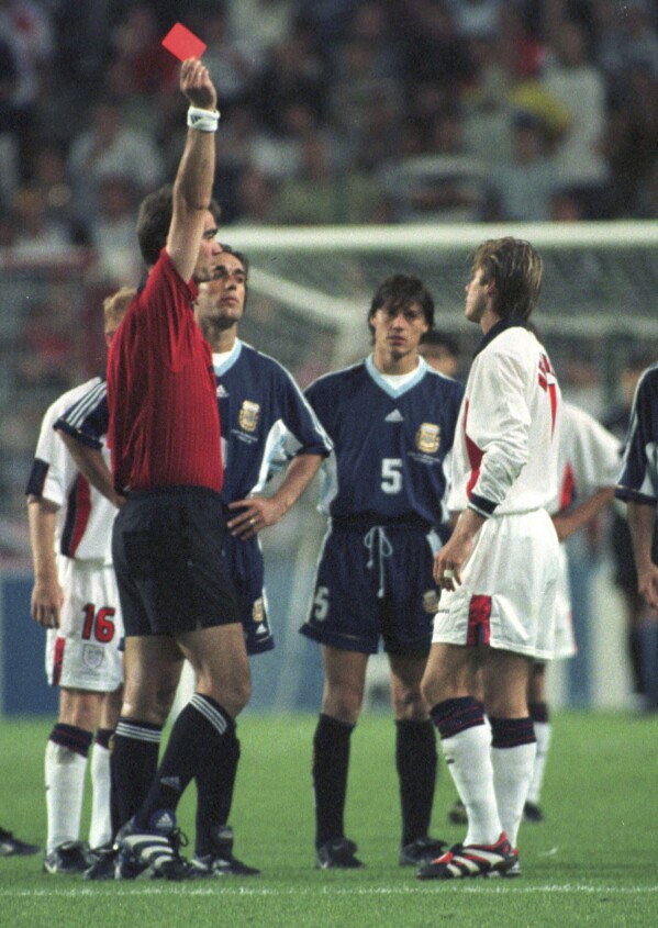 FILE - England's David Beckham receives a red card from Danish referee Kim Milton Nielsen for kicking Argentina's Diego Simeone, during England's World Cup second round soccer match against Argentina, in Saint Etienne, France on June 30, 1998. England lost on penalties after the match ended 2-2. A four-part Netflix series, "Beckham," explores Beckham’s upbringing and his triumphs on the field, but perhaps the most difficult part was revisiting his painful sending off during England’s World Cup match against Argentina. (AP Photo/Denis Doyle, File)
