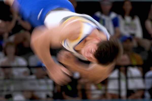 In this photo made with a slow shutter speed, Illia Kovtun, of Ukraine, competes during the men's artistic gymnastics individual floor finals at Bercy Arena at the 2024 Summer Olympics, Saturday, Aug. 3, 2024, in Paris, France. (AP Photo/Charlie Riedel)
