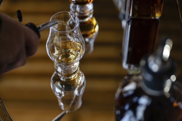 An employee pours a glass of The Bard's product in what will be a new production area at The Bard Distillery in Graham, Ky., Sunday, March 9, 2025. (AP Photo/Jon Cherry)