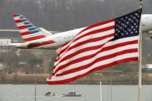Search efforts are seen around a wreckage site of a deadly midair collision between an American Airlines jet and an Army helicopter, in the Potomac River near Ronald Reagan Washington National Airport, Friday, Jan. 31, 2025, in Arlington, Va., as an American Airlines jet lifts off from the airport. (AP Photo/Alex Brandon)