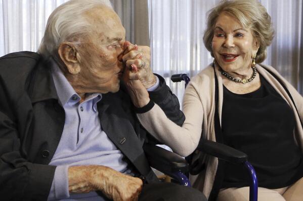 FILE - In this May 4, 2017, file photo, Kirk Douglas kisses his wife Anne's hand, in Los Angeles during a party celebrating his 100th birthday. Anne Douglas, the widow of Kirk Douglas and stepmother of Michael Douglas, died Thursday, April 29, 2021, in California. She was 102. Douglas died at her home in Beverly Hills, according to an obituary provided by spokeswoman Marcia Newberger. No cause of death was given. (AP Photo/Reed Saxon, File)