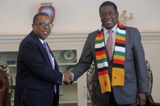 FILE - In this file photo dated Wednesday, Aug, 15, 2018, United States Ambassador to Zimbabwe Brian Nichols, left, during a courtesy call with Zimbabwean President elect Emmerson Mnangagwa at his official State House in Harare.  Zimbabwe’s state-controlled Herald newspaper has reported Monday June 1, 2020, that Nichols has been called to meet with Zimbabwe’s foreign minister over comments Sunday by U.S. national security adviser Robert O’Brien that Zimbabwe is one of several “foreign adversaries” taking advantage of the protests in the U.S. over the death of George Floyd, a black man who pleaded for air as a police officer pressed a knee into his neck. (AP Photo/Tsvangirayi Mukwazhi, FILE)