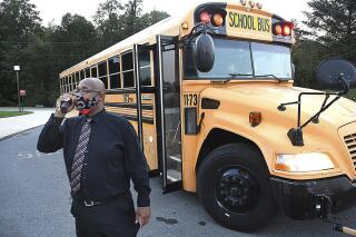 FILE -Beckley Stratton Middle School principal Yahon Smith monitors school buses and parent drop off of students for the first day of school, Sept. 8, 2020, in Beckley, W.Va. A group of Republican lawmakers is proposing a ban on mask mandates in K-12 schools. (Rick Barbero/The Register-Herald via AP)