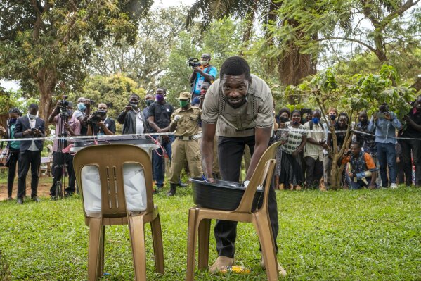 FILE - In this Thursday, Jan. 14, 2021 file photo, Uganda's leading opposition challenger Bobi Wine fills his ballot before voting in Kampala, Uganda. A judge ruled on Monday, Jan. 25, 2021 that Ugandan security forces cannot detain presidential challenger Bobi Wine inside his home, rebuking authorities for holding the candidate under house arrest following a disputed election. (AP Photo/Jerome Delay, File)
