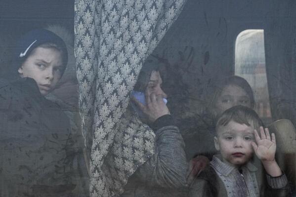 FILE - Internally displaced people look out from a bus at a refugee center in Zaporizhia, Ukraine, Friday, March 25, 2022. Quantifying the toll of Russia’s war in Ukraine remains an elusive goal a year into the conflict. Estimates of the casualties, refugees and economic fallout from the war produce an complete picture of the deaths and suffering. Precise figures may never emerge for some of the categories international organizations are attempting to track. (AP Photo/Evgeniy Maloletka, File)