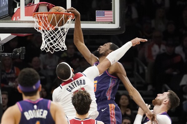 Phoenix Suns' Kevin Durant, center right, is fouled as he dunks againstWashington Wizards' Daniel Gafford, top center left, during the second half of an NBA basketball game in Phoenix, Sunday, Dec. 17, 2023. Phoenix won 112-108. (AP Photo/Darryl Webb)