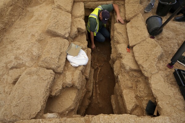 A Palestinian archaeologist removes the sand from a skeleton in a grave at the Roman cemetery in Jebaliya northern Gaza Strip, Saturday, Sept. 23, 2023. The ancient cemetery was uncovered last year during construction of a housing project. Researchers have uncovered 135 graves, including two sarcophagi made of lead. (AP Photo/Adel Hana)