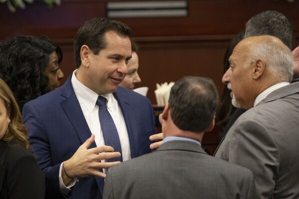 FILE - Nevada Secretary of State Cisco Aguilar, left, talks with Lt. Gov. Stavros Anthony during the opening of the 82nd session of the Nevada Legislature in Carson City, Nev., Feb. 6, 2023. Nevada election officials will start tabulating in-person Election Day votes that morning instead of when polls closed in an attempt to expedite results in the Western swing state known for ballot tabulation that, at times, has stretched close races out for days. (AP Photo/Tom R. Smedes, File)