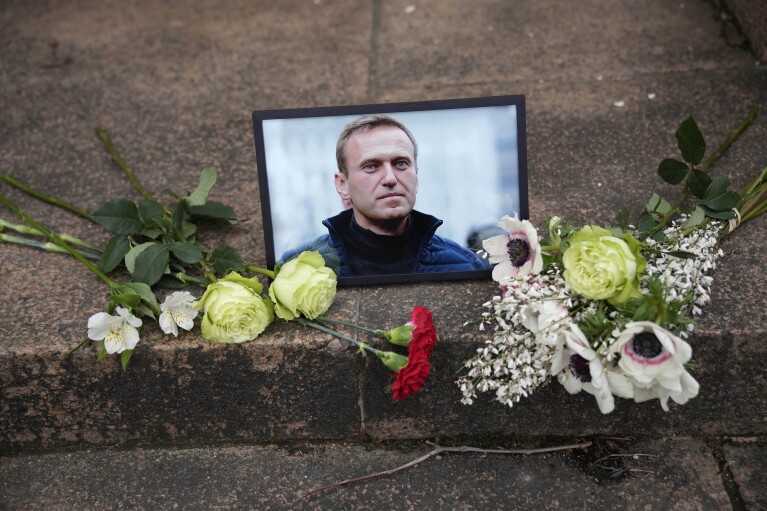 A portrait of jailed Russian opposition leader Alexei Navalny and flowers are placed as people demonstrate near to Russian embassy to France, Friday, Feb. 16, 2024 in Paris. (AP Photo/Christophe Ena)