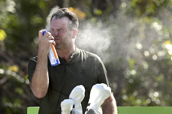 FILE - Mike Flaskey, CEO of Diamond Resorts International, sprays himself with sunscreen before hitting his tee shot on the second hole during the final round of the Tournament of Champions LPGA golf tournament, Sunday, Jan. 24, 2021, in Lake Buena Vista, Fla. (AP Photo/Phelan M. Ebenhack, File)