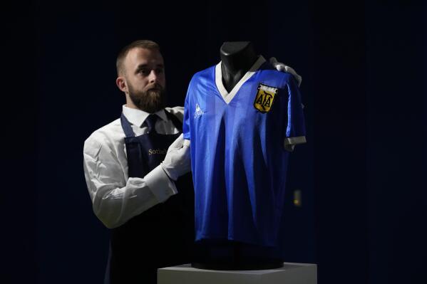FILE - The Argentina football shirt worn by Diego Maradona in the 1986 Mexico World Cup quarterfinal soccer match between Argentina and England, is displayed for photographs at Sotheby's auction house, in London, Wednesday, April 20, 2022. The shirt worn by Maradona when he scored the controversial “Hand of God” goal has sold for 7.1 million pounds ($9.3 million), the highest price ever paid at auction for a piece of sports memorabilia. Auctioneer Sotheby’s sold the shirt in an online auction that closed Wednesday, May 4, 2022. (AP Photo/Matt Dunham, File)