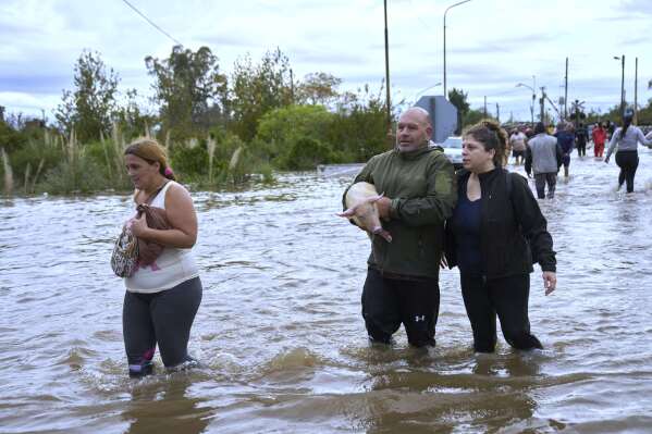 Residents wade through flooded streets following heavy rains in Campana, Argentina, Saturday, May 17, 2025. (AP Photo/Rodrigo Abd)