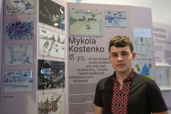 Drawings by Mykola Kostenko, pictured, are part of the War Diaries exhibition, showcasing the personal diaries of Ukrainian children who have witnessed the war, hosted by the Amsterdam city hall , Netherlands, Thursday, Aug. 17, 2023. The city where Anne Frank wrote her World War II diary while hiding with her family from the brutal Nazi occupation is hosting an exhibition with grim echoes of her plight more than three quarters of a century later.(AP Photo/Peter Dejong)