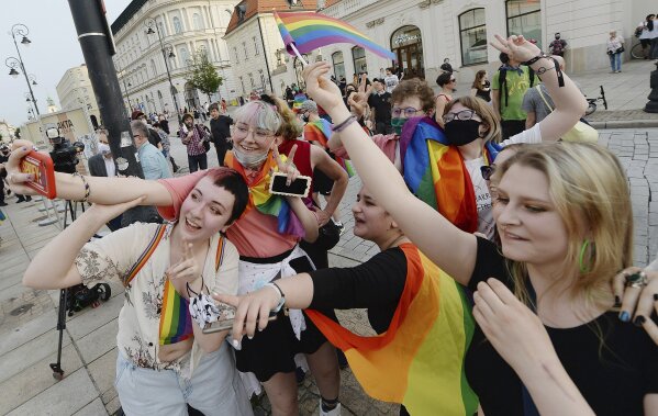 People, with Rainbow flags dance as they take part in rainbow disco flashmob in front of the Presidential Palace in Warsaw, Poland, Thursday, June 11, 2020. Polish President Andrzej Duda signed a document called Family Card which is homophobic and discriminating in the perception of the LGBT community. (AP Photo/Czarek Sokolowski)