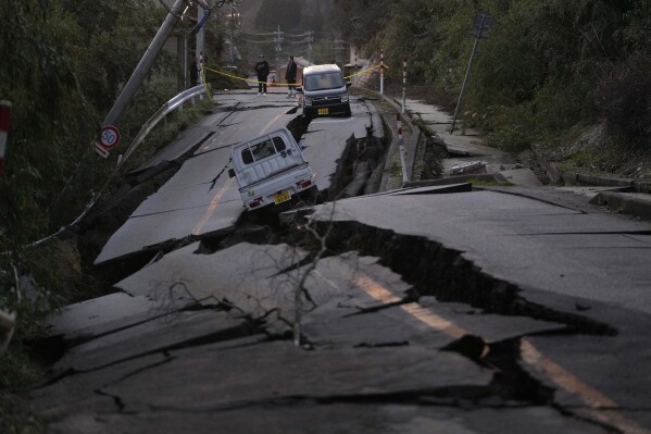 Bystanders look at damage near Noto town in the Noto peninsula facing the Sea of Japan, northwest of Tokyo, Tuesday, Jan. 2, 2024, following Monday's deadly earthquake. (AP Photo/Hiro Komae)