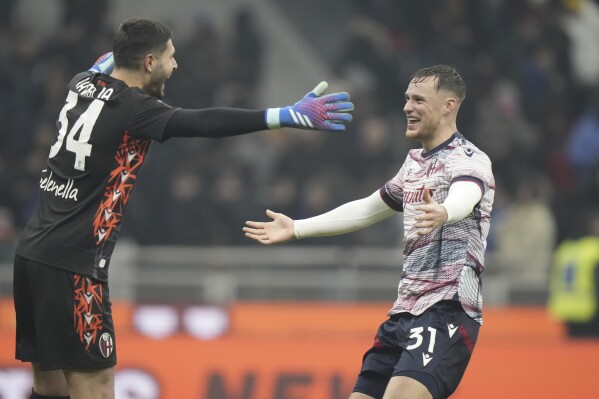 Bologna's goalkeeper Federico Ravaglia and Bologna's Sam Beukema celebrate at the end of the Italian Cup round of 16 soccer match between Inter Milan and Bologna, at the San Siro stadium in Milan, Italy, Wednesday, Dec. 20, 2023. (AP Photo/Luca Bruno)