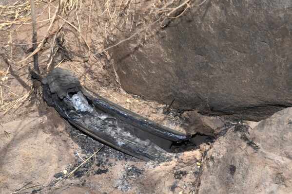 This photo provided by the Morgan & Morgan law firm shows what appears to be a partially buried and burned automotive tire located in the overgrown gully where investigators suspect fire may have rekindled on the afternoon of Aug. 8, 2023, before spreading through town of Lahaina, Maui, Hawaii, seen on Aug. 29, 2023. Investigators are examining pieces of evidence as they seek to solve the mystery of how a small, wind-whipped fire sparked by downed power lines and declared extinguished flare up again hours later into a devastating inferno. (Morgan & Morgan via AP)