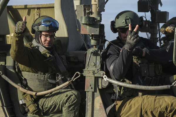 Israëlische soldaten zwaaien vanuit hun auto op de terugweg van de Gazastrook, in het zuiden van Israël, vlakbij de grens met Gaza, donderdag 1 februari 2024. (AP Photo/Tsafrir Abayov)