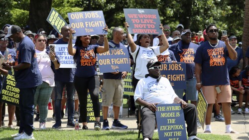 Workers hold signs supporting labor organizers in their legal battle over container loading jobs at a rally in Columbia, S.C. on Wednesday, July 12, 2023. A federal appeals court is currently weighing a National Labor Relations Board decision that upheld unionized dockworkers' right to exclusively staff the cranes at Hugh K. Leatherman Terminal in Charleston, South Carolina. (AP Photo/James Pollard)