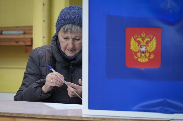 A woman checks a pen prior to fill her ballot at a pooling station during a presidential election in St. Petersburg, Russia, Friday, March 15, 2024. Voters in Russia are heading to the polls for a presidential election that is all but certain to extend President Vladimir Putin's rule after he clamped down on dissent. (AP Photo/Dmitri Lovetsky)