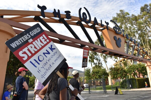 Picketers carry signs outside Disney studios on Monday, July 17, 2023, in Burbank, Calif. The actors strike comes more than two months after screenwriters began striking in their bid to get better pay and working conditions and have clear guidelines around the use of AI in film and television productions. (Jordan Strauss/Invision/AP)