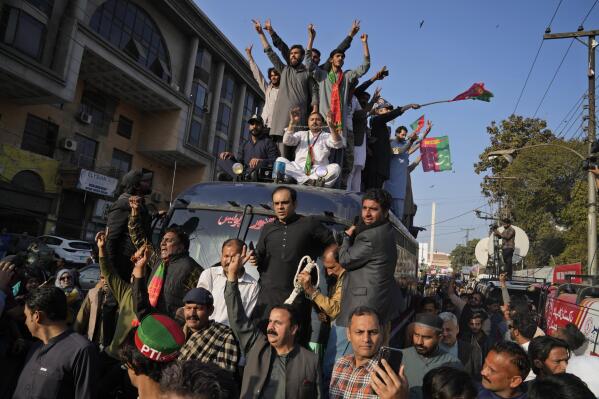 Supporters of Pakistan's former prime minister Imran Khan's 'Pakistan Tehreek-e-Insaf' party climb on a police van and chat ant government slogans during a rally, in Lahore, Pakistan, Wednesday, Feb. 22, 2023. Hundreds of supporters of Pakistan's former prime minister on Wednesday defied a ban on rallies in a commercial area of the city of Lahore, taunting police and asking to be arrested en masse. (AP Photo/K.M. Chaudary)