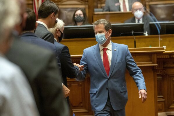 FILE - In this Friday, June 26, 2020, file photo, Georgia Gov. Brian Kemp is greeted as he visits the House Chambers on Sine Die, day 40, of the legislative session in Atlanta. Kemp says he hasn’t yet weighed whether the state will take legal action against local governments trying to impose mask requirements. The Republican held a news conference Wednesday, July 1, 2020, before departing on a statewide tour to promote wearing a mask, but said he won’t mandate it. (Alyssa Pointer/Atlanta Journal-Constitution via AP, File)