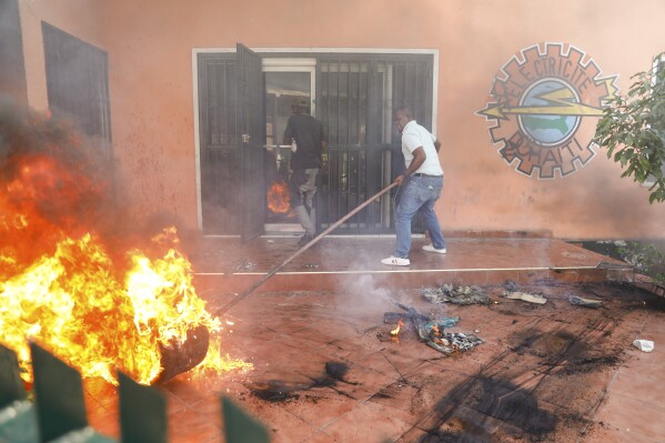 Workers put down a fire set at an office of Haiti's power company during a protest to demand the resignation of the Prime Minister Ariel Henry in Port-au-Prince, Haiti, Friday, March 1, 2024. (AP Photo/Odelyn Joseph)