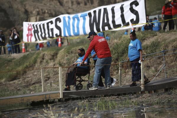 People living in Mexico cross a temporary bridge to meet with relatives living in the U.S., during the 10th annual "Hugs not Walls" event on a stretch of the Rio Grande, in Ciudad Juarez, Mexico, Saturday, May 6, 2023. The brief family reunions are part of a campaign sponsored by the Border Network for Human Rights, an immigration rights group. (AP Photo/Christian Chavez)