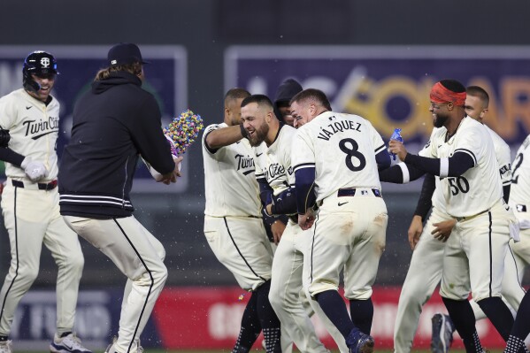 Minnesota Twins Alex Kirilloff (19) is surrounded by teammates in celebration after he drove in the winning run against the Chicago White Sox during the ninth inning of a baseball game Tuesday, April 23, 2024, in Minneapolis. (AP Photo/Stacy Bengs)