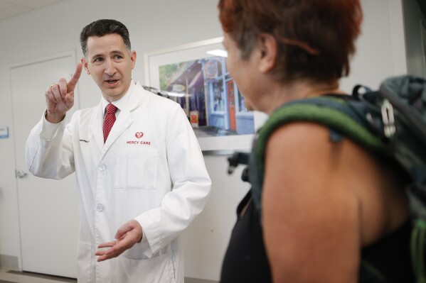 FILE - Dr. Reed Pitre, director of psychiatry and interim chief medical officer at Mercy Care clinic, left, speaks with a patient after her appointment, June 27, 2023, in Atlanta. Some Republican legislative leaders say they want to examine broader health care coverage through Georgia's Medicaid program in 2024. (AP Photo/Alex Slitz, File)