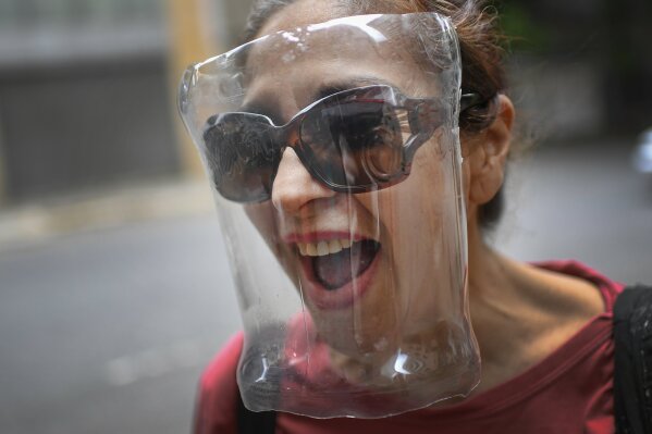 A woman wears a makeshift face shield made from a plastic bottle container as a precaution against the new coronavirus, in Caracas, Venezuela, Saturday, April 18, 2020. (AP Photo/Matias Delacroix)