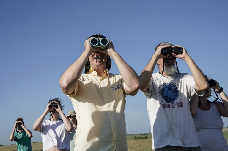 Jason St. Sauver, center, senior manager for education at Spring Creek Prairie Audubon Center, looks through binoculars while leading a grassland bird tour, Tuesday, June 20, 2023, in Denton, Neb. (AP Photo/Joshua A. Bickel)