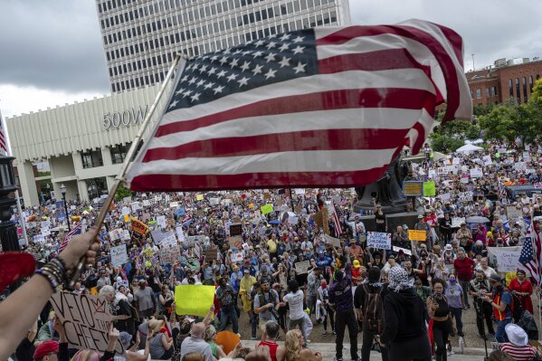 A person waves an American flag as demonstrators gather at Metro Hall during a "No Kings" protest on Saturday, June 14, 2025, in Louisville, Ky. (AP Photo/Jon Cherry)